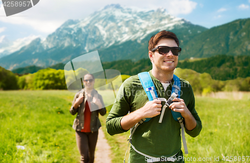 Image of happy couple with backpacks hiking outdoors