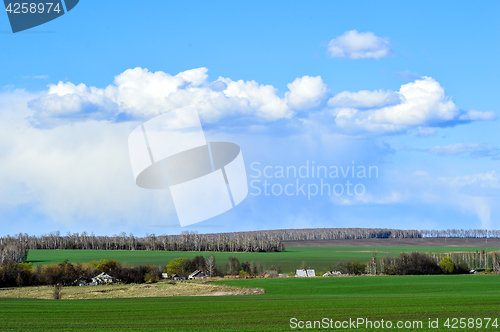 Image of Rural landscape with a green field, clouds and farm