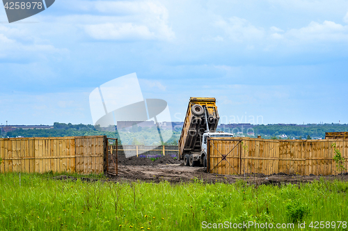 Image of The dumper brought and dumps earth in the open warehouse