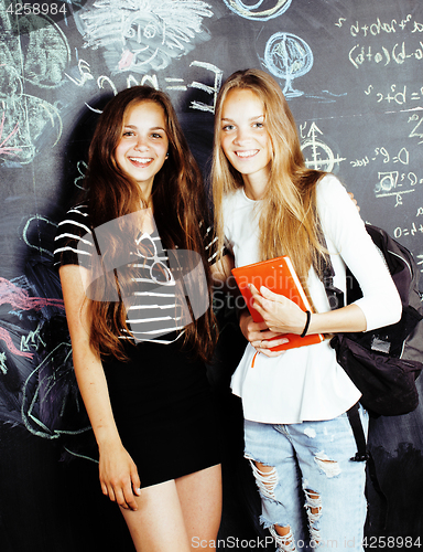 Image of back to school after summer vacations, two teen real girls in classroom with blackboard painted together, lifestyle people concept