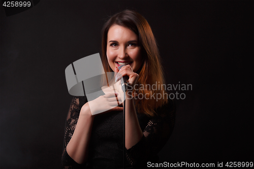 Image of Brunette in dress with microphone
