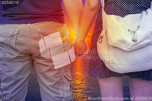 Image of Young couple holding hands on beach at sunset
