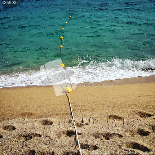 Image of Rope with floats and footprints on the beach