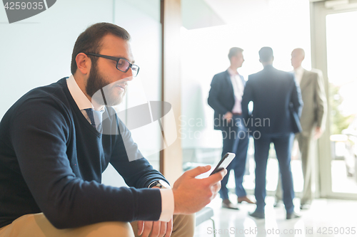 Image of Businessman using smart phone while sitting in waiting room.