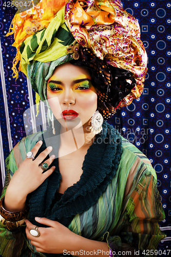 Image of beauty bright woman with creative make up, many shawls on head l