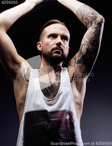 Image of A man with tattooes on his arms. Silhouette of muscular body. caucasian brutal hipster guy with modern haircut, looking like criminal