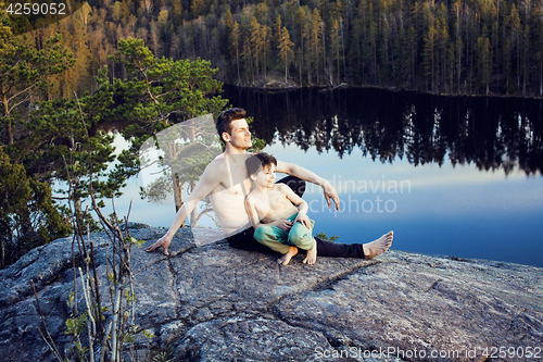 Image of middle age man with little cute son doing sport yoga on the top of the mountain together, happy family lifestyle people outdoor, summer wild nature for training