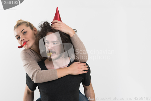 Image of couple in party hats blowing in whistle