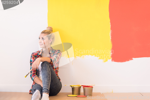 Image of young female painter sitting on floor