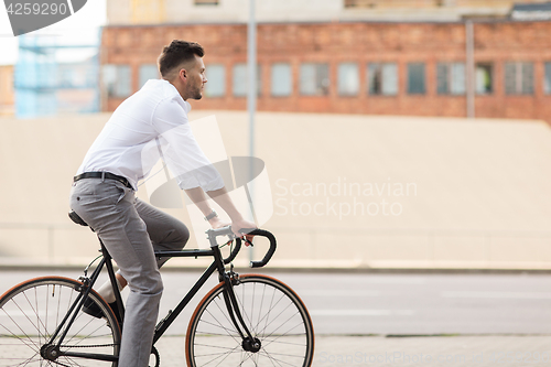 Image of man with headphones riding bicycle on city street