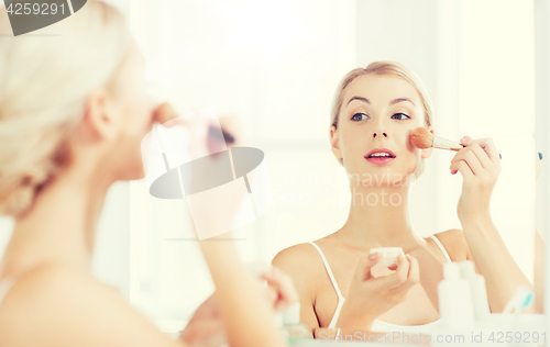 Image of woman with makeup brush and powder at bathroom