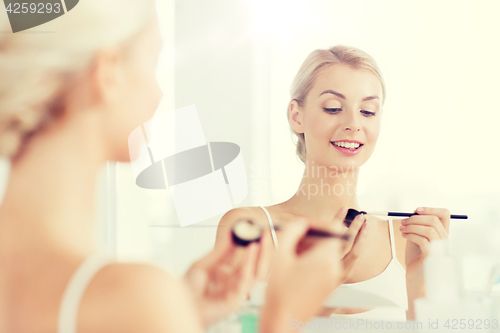 Image of woman with makeup brush and eyeshade at bathroom