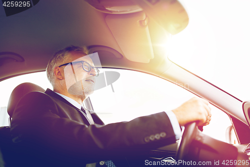 Image of happy senior businessman driving car