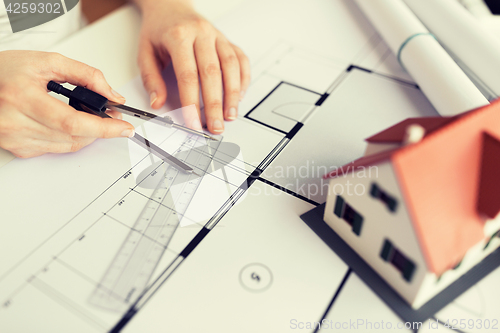 Image of close up of hands with compass measuring blueprint