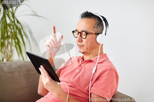 Image of man with tablet pc and headphones at home