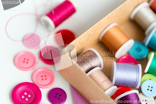 Image of box with thread spools and sewing buttons on table