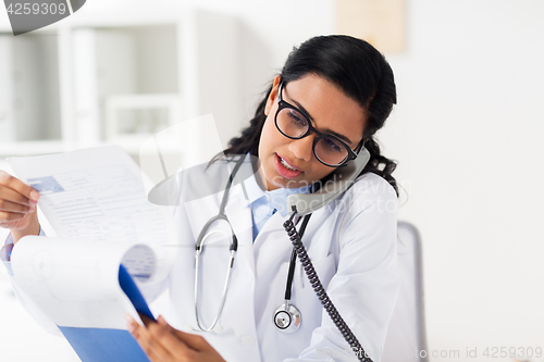 Image of doctor with clipboard calling on phone at hospital