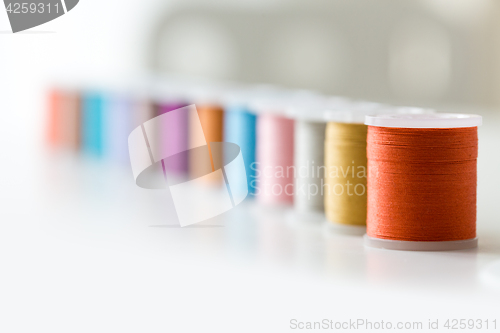 Image of row of colorful thread spools on table