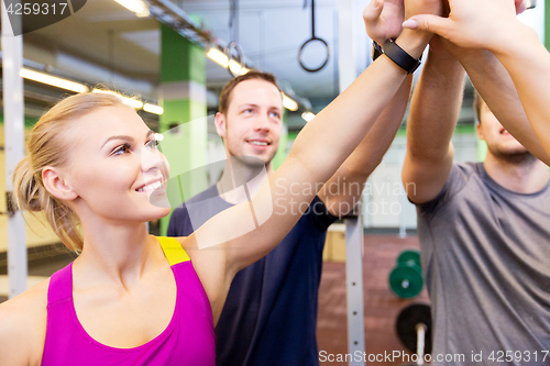 Image of group of happy friends making high five in gym