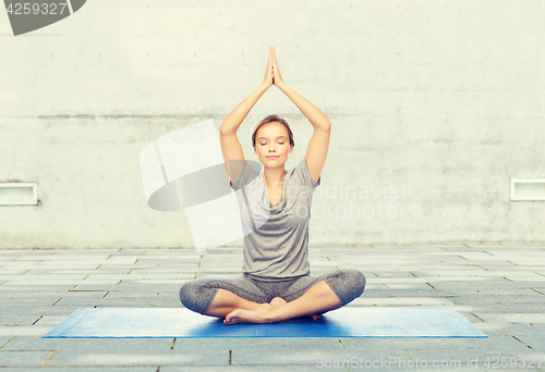 Image of woman making yoga meditation in lotus pose on mat