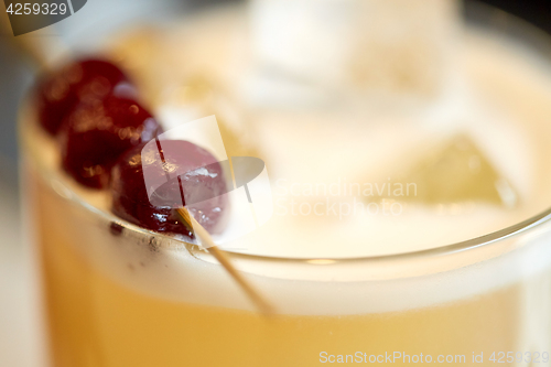 Image of close up of cocktail glass with cherries at bar