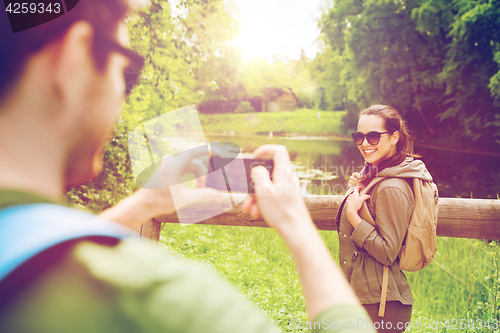 Image of couple with backpacks taking picture by smartphone