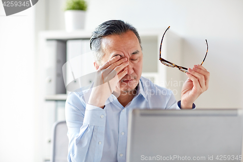 Image of tired businessman with glasses at laptop in office