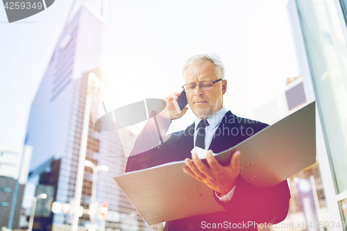 Image of senior businessman calling on smartphone in city