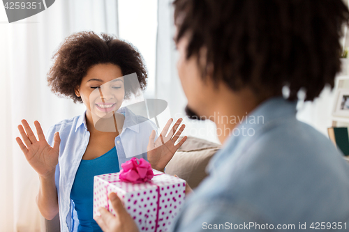 Image of happy couple with gift box at home