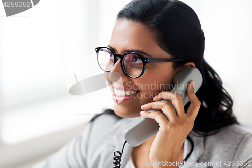 Image of smiling businesswoman calling on phone at office