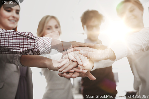 Image of happy business team with hands on top at office