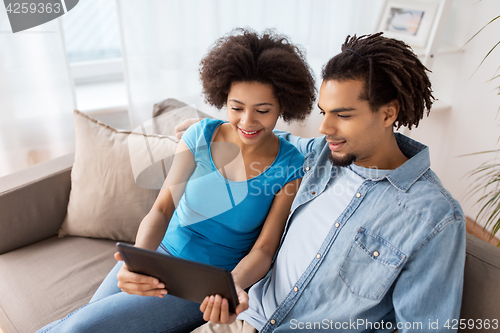 Image of smiling happy couple with tablet pc at home