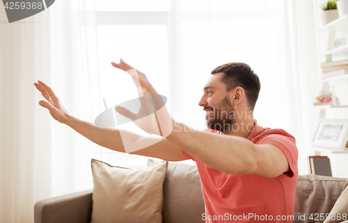 Image of happy man touching something imaginary at home
