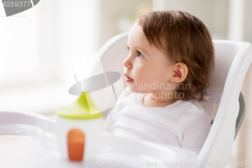 Image of happy baby girl sitting in highchair at home