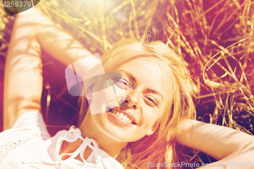 Image of happy young woman lying on cereal field