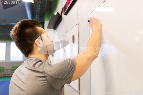 Image of man writing note to whiteboard in gym