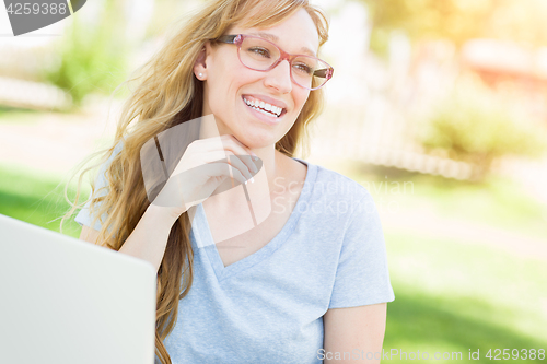 Image of Young Adult Woman Wearing Glasses Outdoors Using Her Laptop.