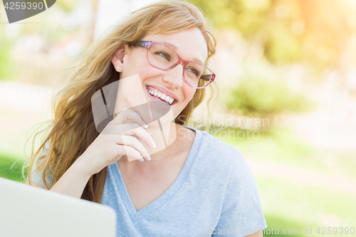 Image of Young Adult Woman Wearing Glasses Outdoors Using Her Laptop.
