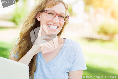 Image of Young Adult Woman Wearing Glasses Outdoors Using Her Laptop.