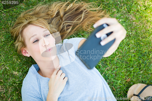 Image of Young Adult Woman Laying in Grass Taking a Selfie with Her Smart