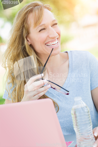 Image of Young Adult Woman With Glasses Outdoors Using Her Laptop.