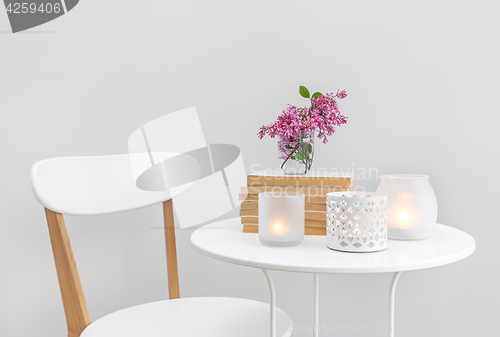 Image of Candle lights, books and flowers on a white table