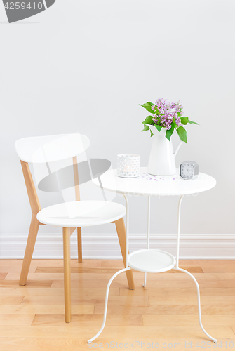 Image of Elegant interior with table, chair and bouquet of lilacs