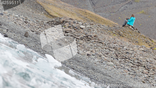 Image of Woman sitting on the beach at Jokulsarlon glacier lagoon - Icela