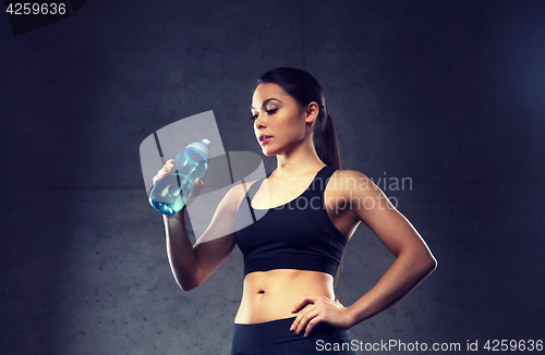 Image of woman drinking water from bottle in gym