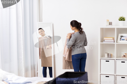 Image of woman packing travel bag at home or hotel room