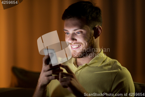 Image of happy young man with smartphone at night