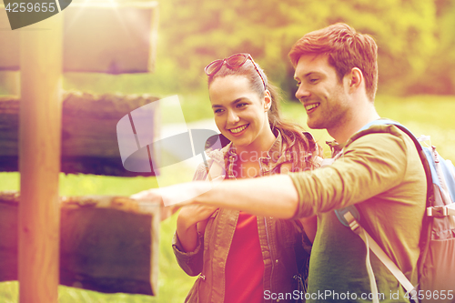 Image of smiling couple at signpost with backpacks hiking