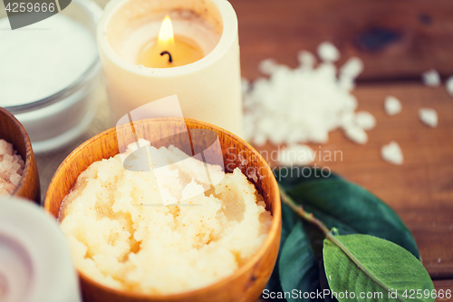 Image of close up of natural body scrub and candle on wood