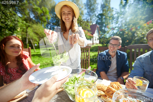 Image of happy friends having dinner at summer garden party